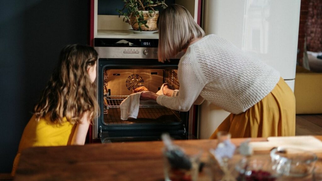 donna e bambina cucinano nel forno