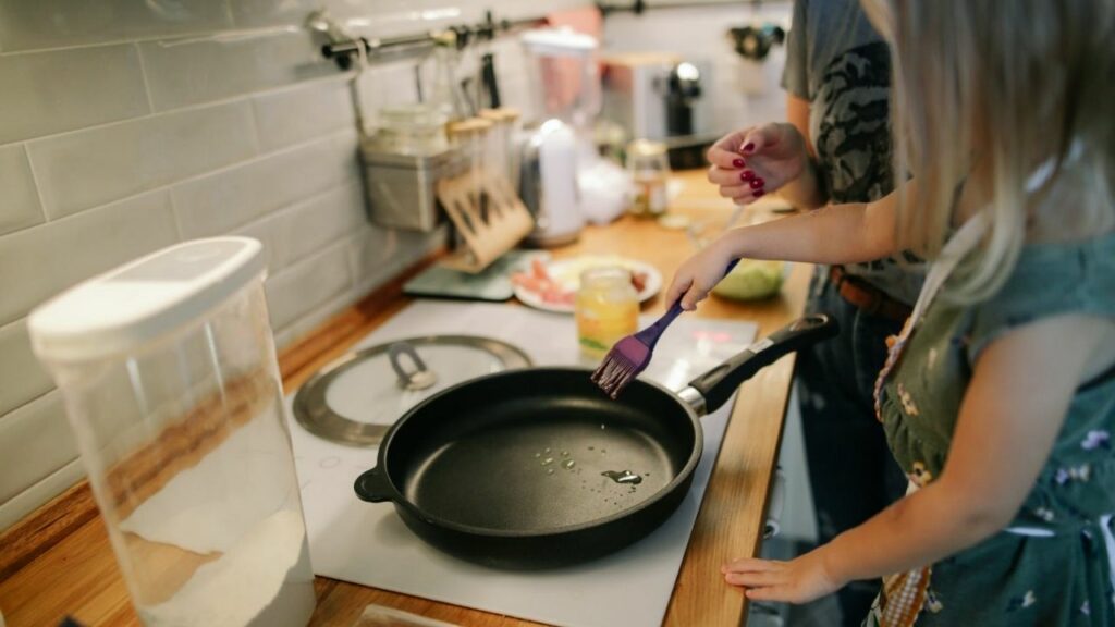 donna in cucina che cucina in padella