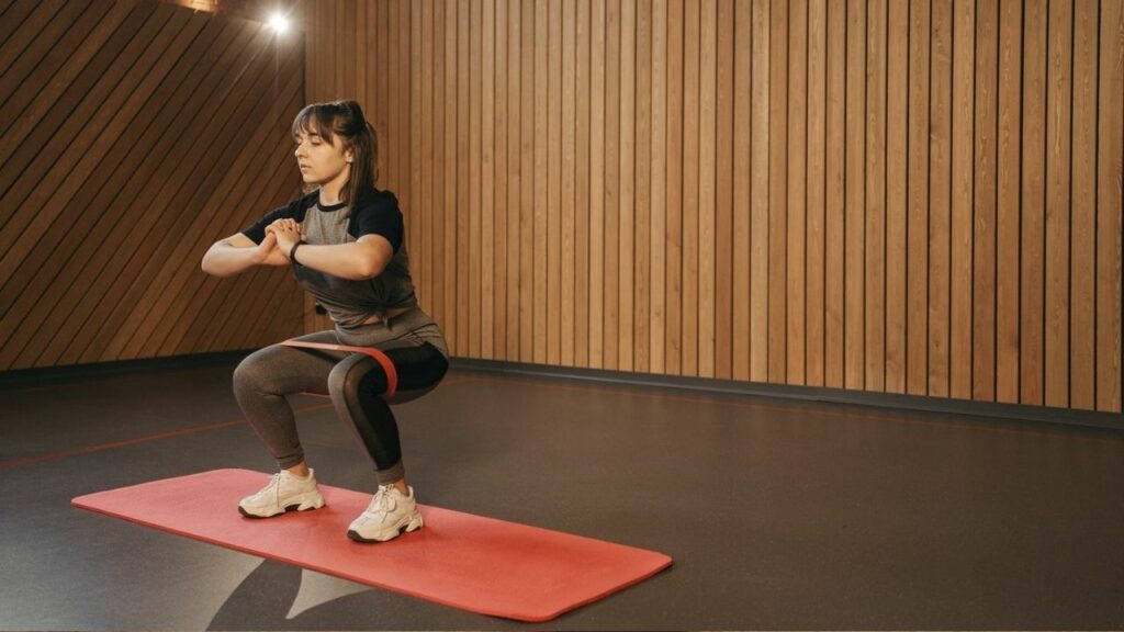 ragazza fa squat con la fascia su un tappetino