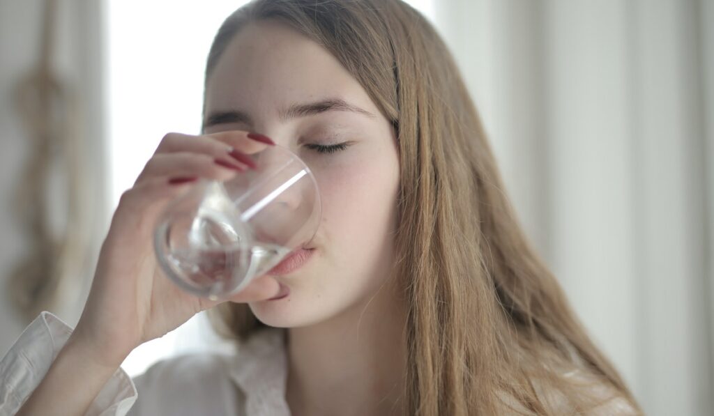 Ragazza beve bicchiere d'acqua