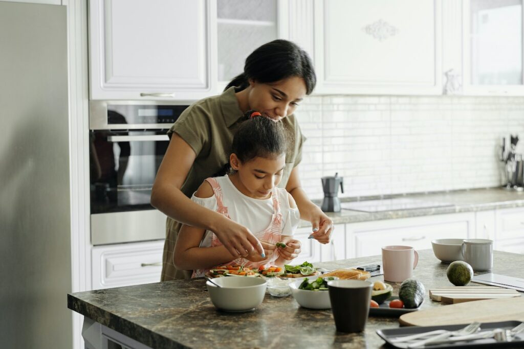 Mamma cucina con la figlia piccola