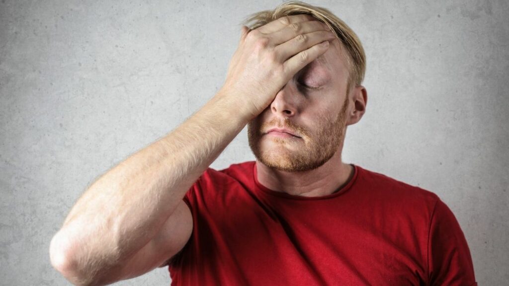 uomo con maglia rossa e mal di testa