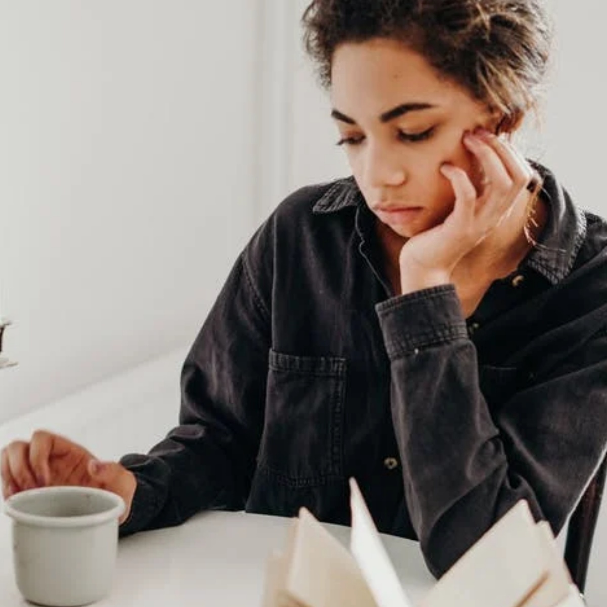 ragazza triste con tisana e libro